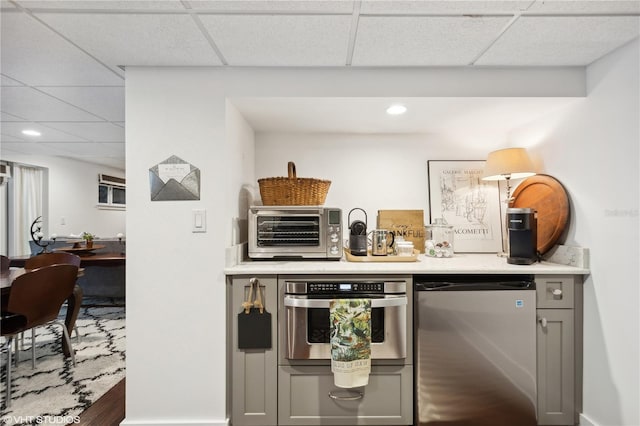 kitchen featuring a drop ceiling, gray cabinets, and appliances with stainless steel finishes