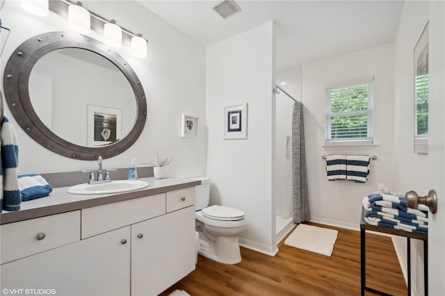 bathroom featuring wood-type flooring, vanity, toilet, and curtained shower