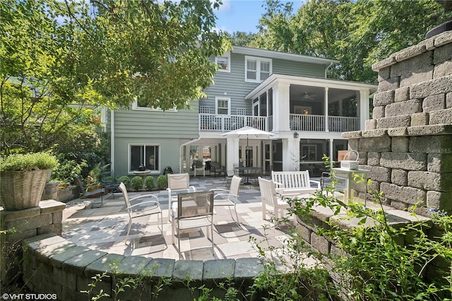 rear view of property featuring a sunroom, a patio, and a balcony