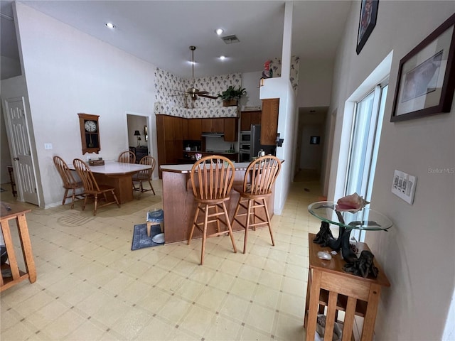 kitchen featuring a high ceiling, double oven, a kitchen breakfast bar, and kitchen peninsula