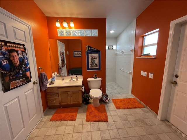 bathroom featuring toilet, a tile shower, and vanity