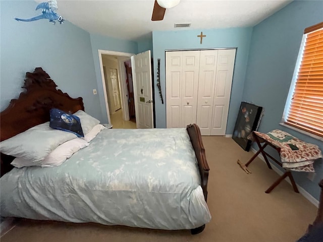 carpeted bedroom with a closet, visible vents, and ceiling fan