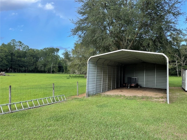 view of outdoor structure with a carport, fence, and driveway