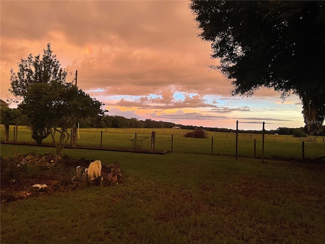 yard at dusk with fence and a rural view