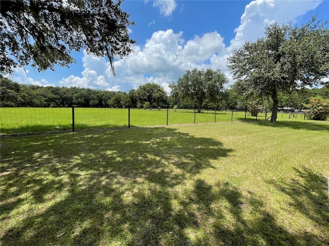 view of yard with fence and a rural view