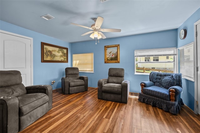 living area with visible vents, a ceiling fan, and wood finished floors
