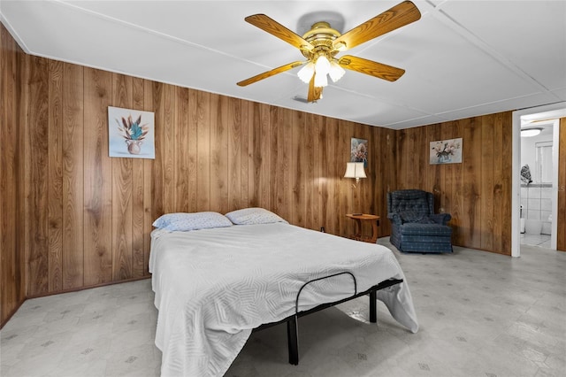bedroom with a ceiling fan, light floors, and wood walls