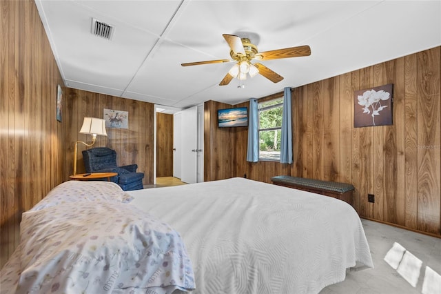 bedroom featuring carpet flooring, visible vents, wood walls, and ceiling fan