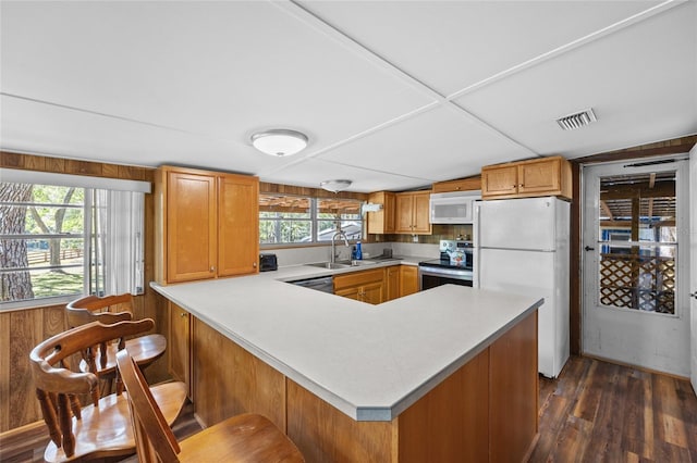 kitchen featuring visible vents, a peninsula, a sink, stainless steel appliances, and light countertops