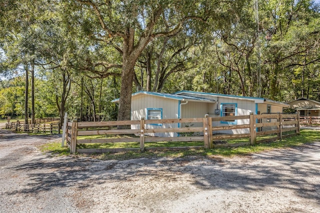 view of front of house featuring a view of trees and fence