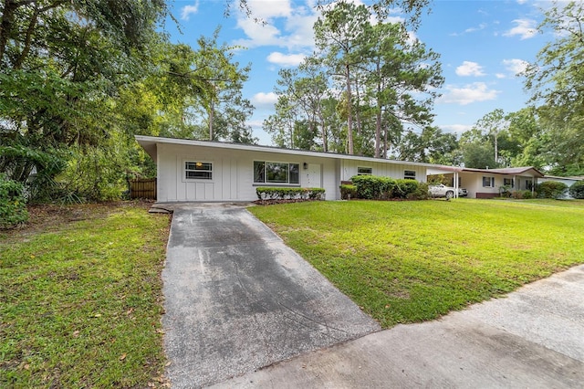 ranch-style house featuring driveway, a front lawn, and board and batten siding