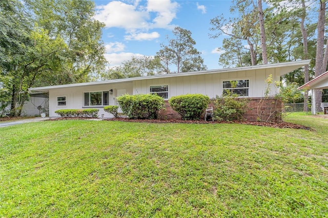 single story home featuring board and batten siding, brick siding, a front lawn, and fence