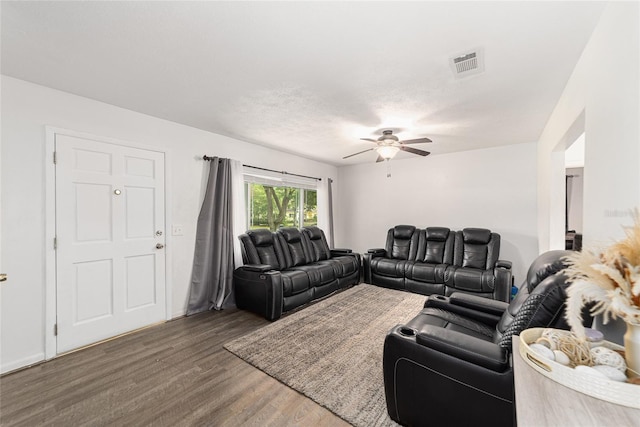 living room featuring dark wood-type flooring, visible vents, and a ceiling fan