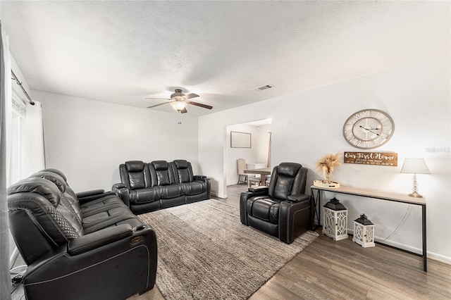 living area with visible vents, a ceiling fan, a textured ceiling, wood finished floors, and baseboards