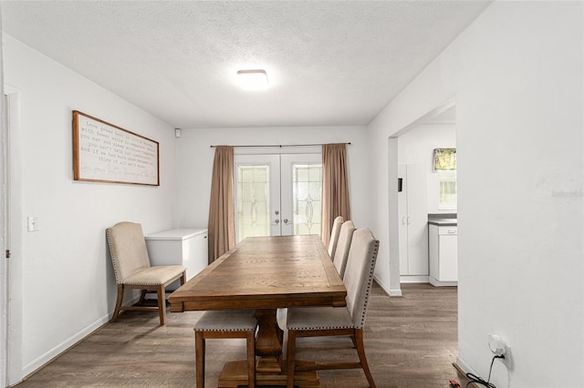 dining space featuring a textured ceiling, baseboards, wood finished floors, and french doors