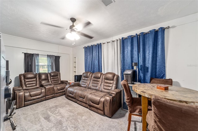 living room featuring ceiling fan, visible vents, a textured ceiling, and light colored carpet