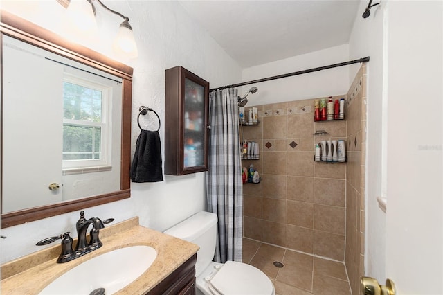 full bathroom with tiled shower, vanity, and toilet