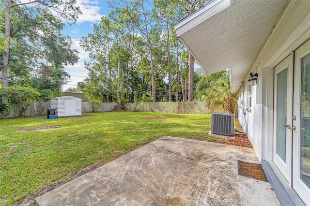 view of yard with an outbuilding, a patio, a fenced backyard, central AC, and a storage unit