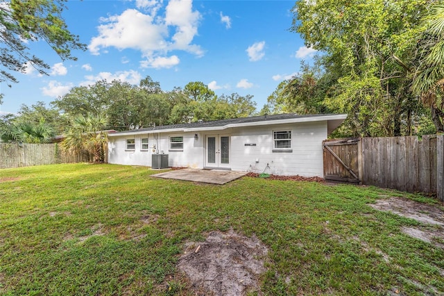 back of property with a patio, a fenced backyard, a yard, cooling unit, and french doors