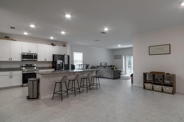 kitchen with a kitchen breakfast bar, an island with sink, a healthy amount of sunlight, and appliances with stainless steel finishes