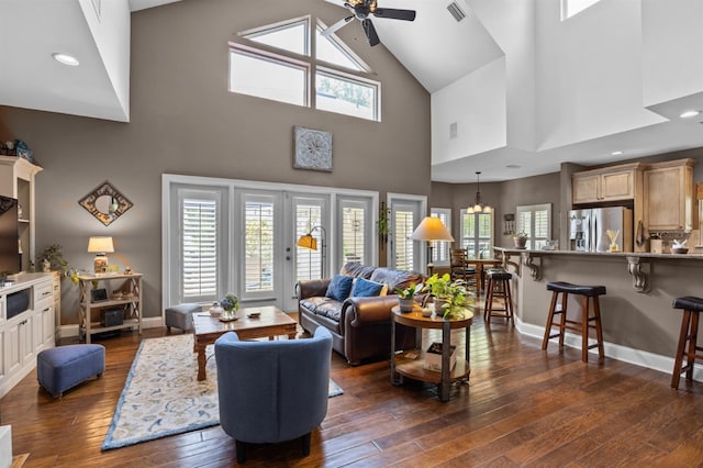 living room featuring ceiling fan, a towering ceiling, dark wood-type flooring, and plenty of natural light