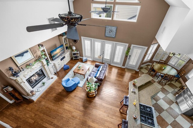 living room with ceiling fan, hardwood / wood-style flooring, and a high ceiling