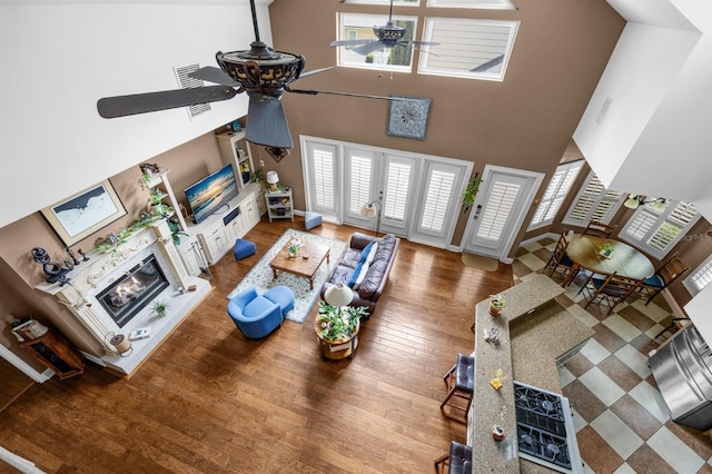 living room with hardwood / wood-style flooring, ceiling fan, french doors, and a towering ceiling