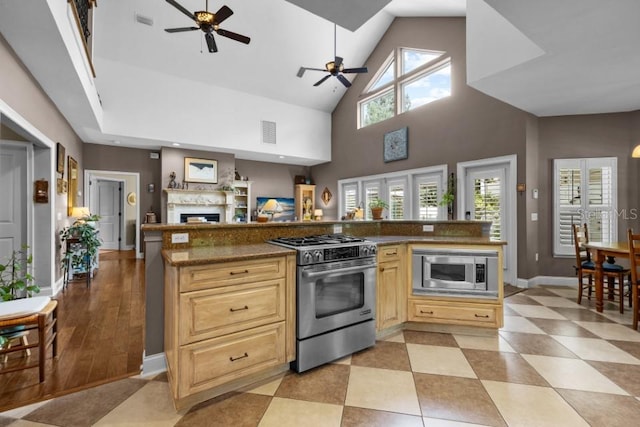 kitchen featuring stainless steel appliances, high vaulted ceiling, light tile patterned floors, light brown cabinetry, and ceiling fan