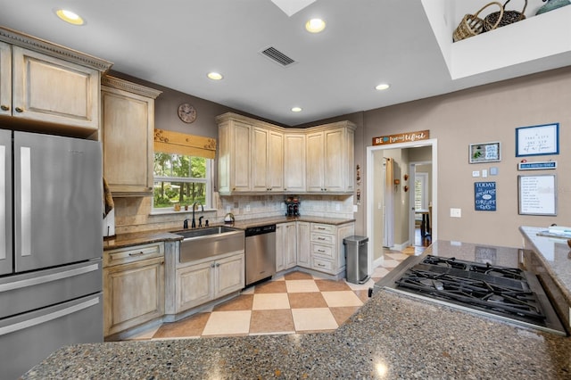 kitchen with backsplash, sink, dark stone countertops, light tile patterned flooring, and stainless steel appliances