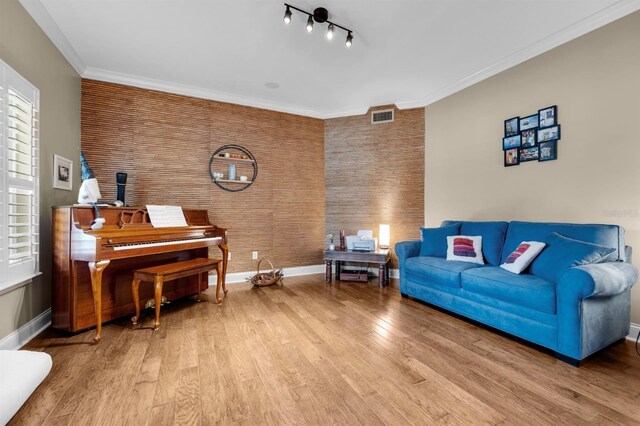 living room with rail lighting, hardwood / wood-style floors, and brick wall