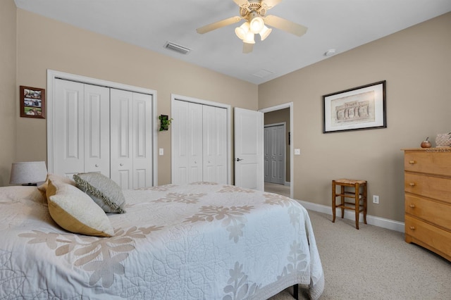 carpeted bedroom with ceiling fan and two closets