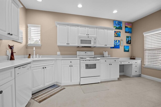 kitchen with white cabinets, sink, white appliances, and light tile patterned floors