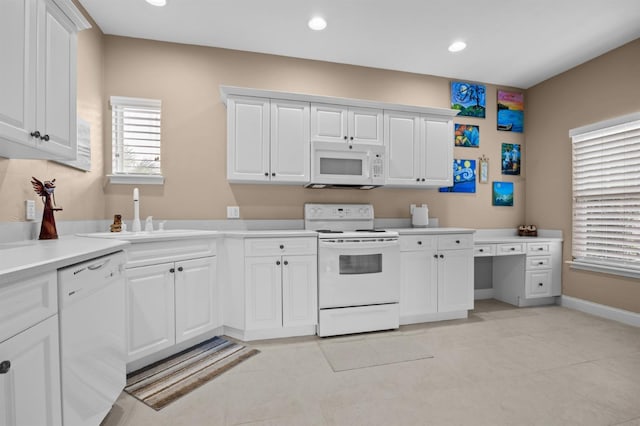 kitchen with white cabinetry, sink, light tile patterned flooring, and white appliances