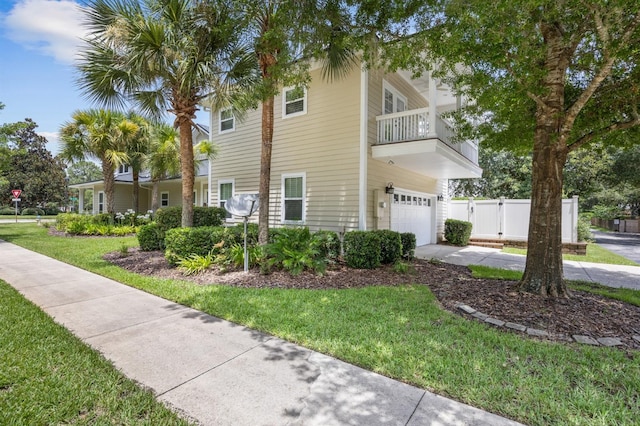 view of side of property with a garage, a balcony, and a lawn