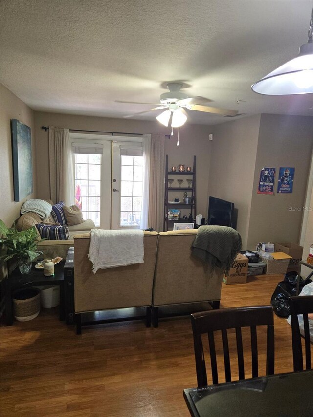 living room with a textured ceiling, french doors, hardwood / wood-style floors, and ceiling fan