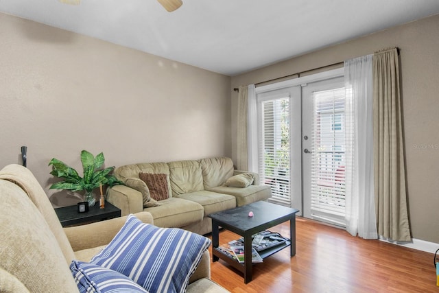living area with wood finished floors, a ceiling fan, and baseboards