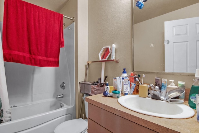 full bath with a textured wall, washtub / shower combination, vanity, and toilet