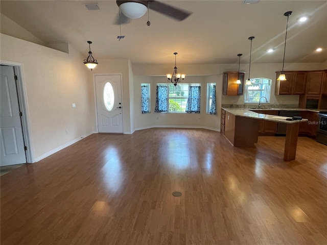 kitchen with pendant lighting, ceiling fan with notable chandelier, vaulted ceiling, and hardwood / wood-style flooring