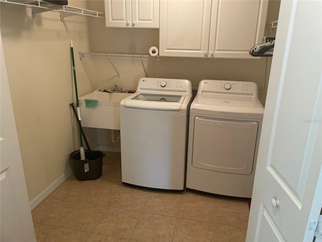 laundry area featuring cabinets, sink, light tile patterned floors, and washing machine and clothes dryer