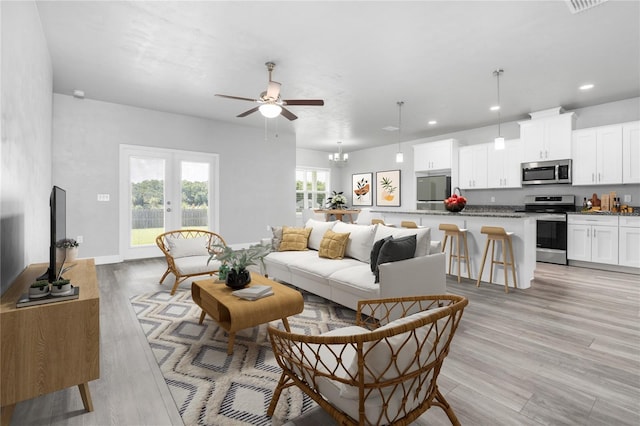 living room featuring french doors, ceiling fan with notable chandelier, and light wood-type flooring