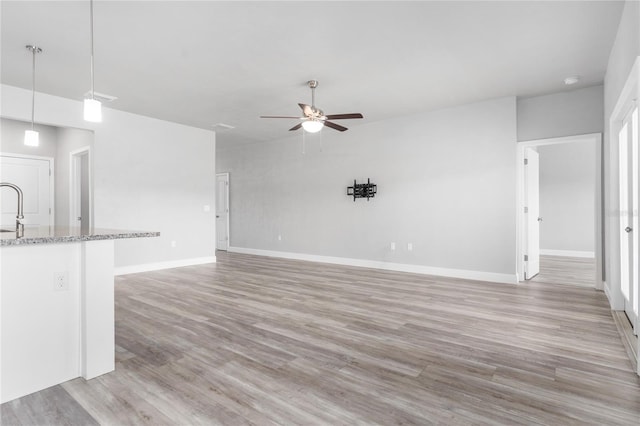 unfurnished living room with ceiling fan and light hardwood / wood-style floors