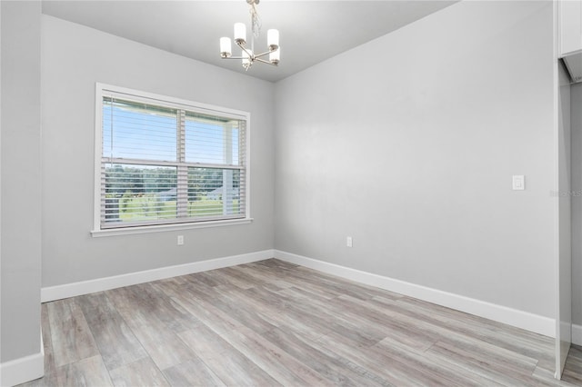 empty room with a chandelier and light hardwood / wood-style flooring