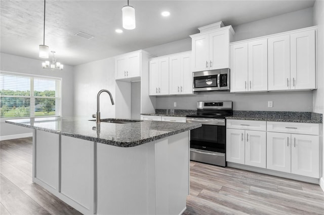 kitchen with an island with sink, sink, white cabinets, hanging light fixtures, and stainless steel appliances