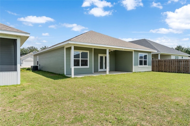 rear view of house featuring cooling unit, a patio area, and a lawn