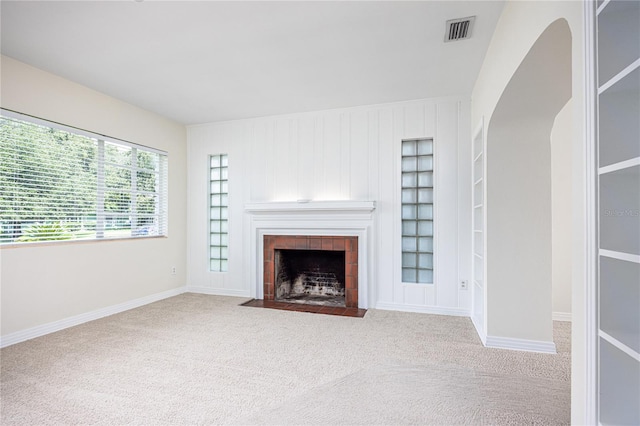 unfurnished living room featuring a fireplace and light colored carpet