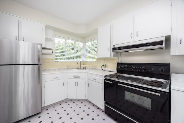 kitchen featuring under cabinet range hood, electric range, a sink, light countertops, and freestanding refrigerator