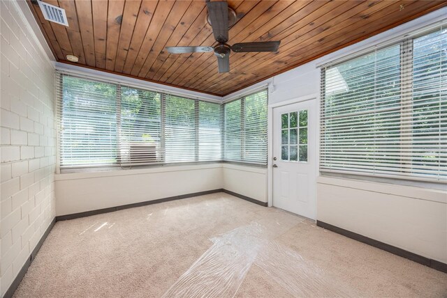 unfurnished sunroom featuring ceiling fan, plenty of natural light, and wooden ceiling