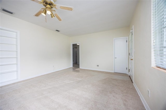 spare room featuring light carpet, baseboards, built in shelves, and visible vents