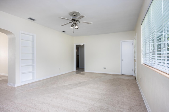 carpeted spare room featuring ceiling fan and built in shelves