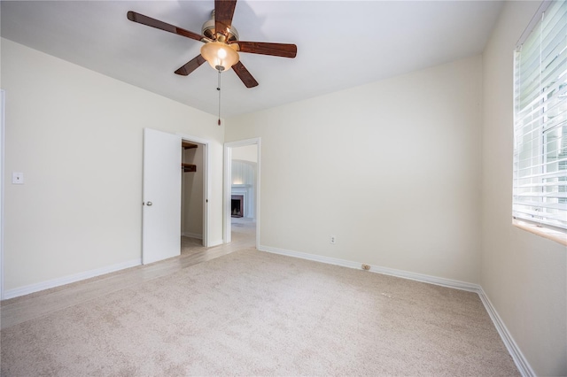 unfurnished room featuring plenty of natural light, a fireplace, baseboards, and light colored carpet